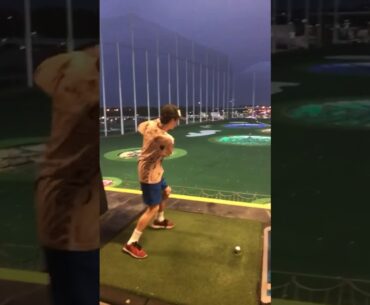 Kid throws golf club off top golf floor.