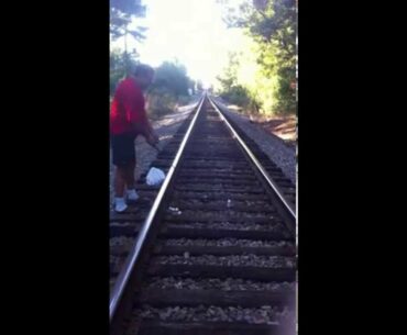 Golfer hitting golf balls down railroad tracks