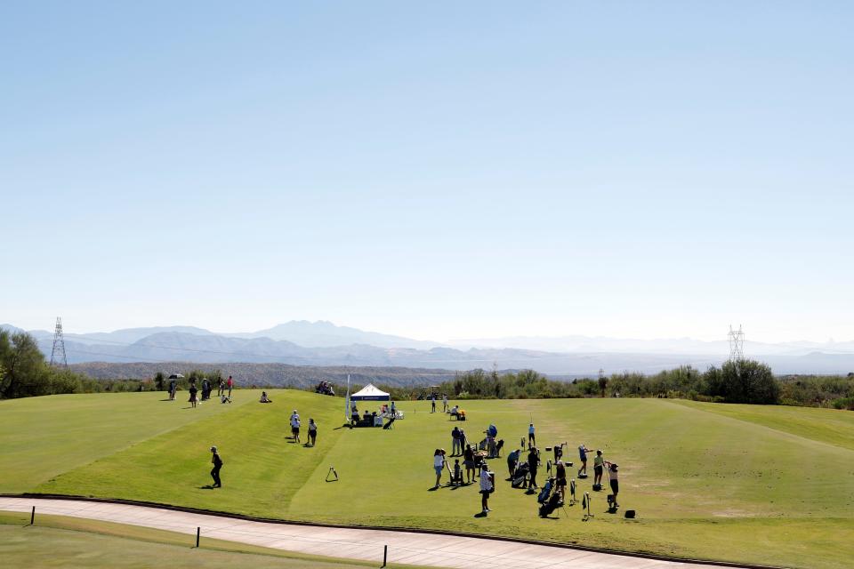 Golfers on a green with a view of mountains in the distance.