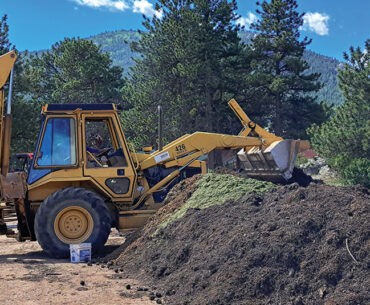 A bulldozer rotates a large compost pile outside