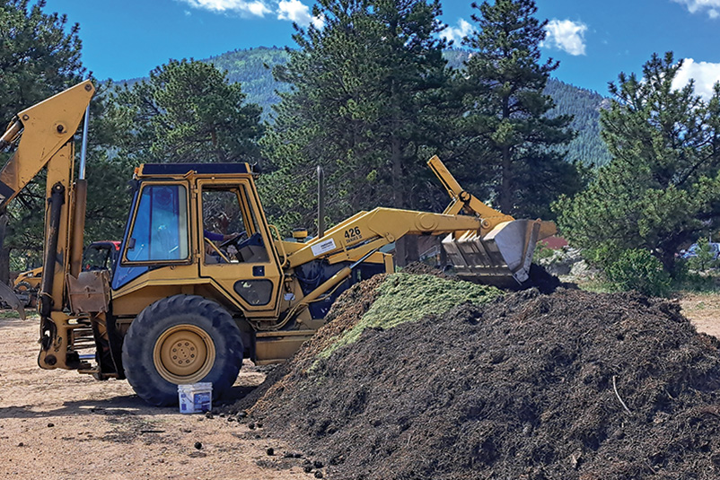 A bulldozer rotates a large compost pile outside