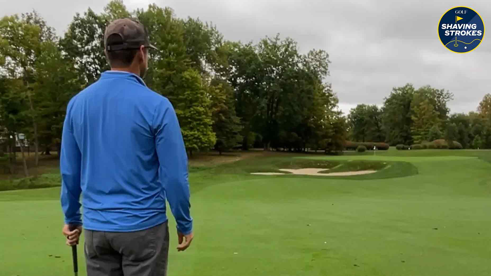 Golfer stares at golf green before hitting shot on golf course.